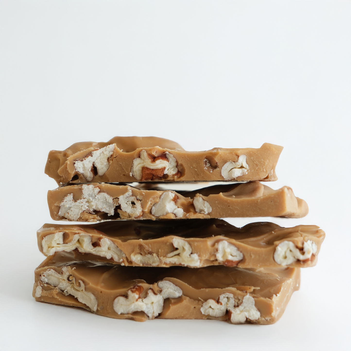 Stack of salted caramel pecan chcocolate bars on a white background