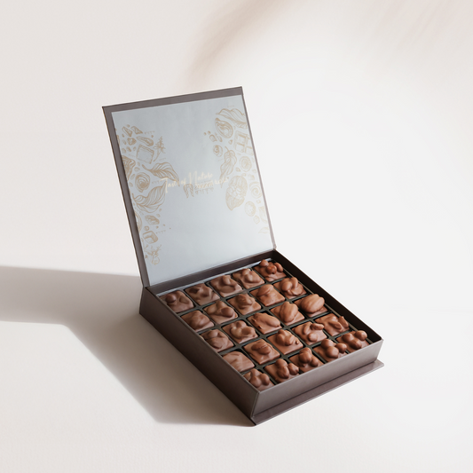 Open box of chocolates with decorative lid on a light background