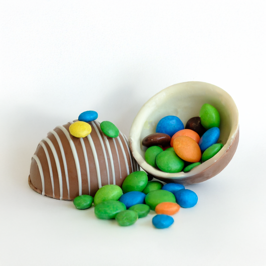 Chocolate egg with colorful candies spilling out on a white background