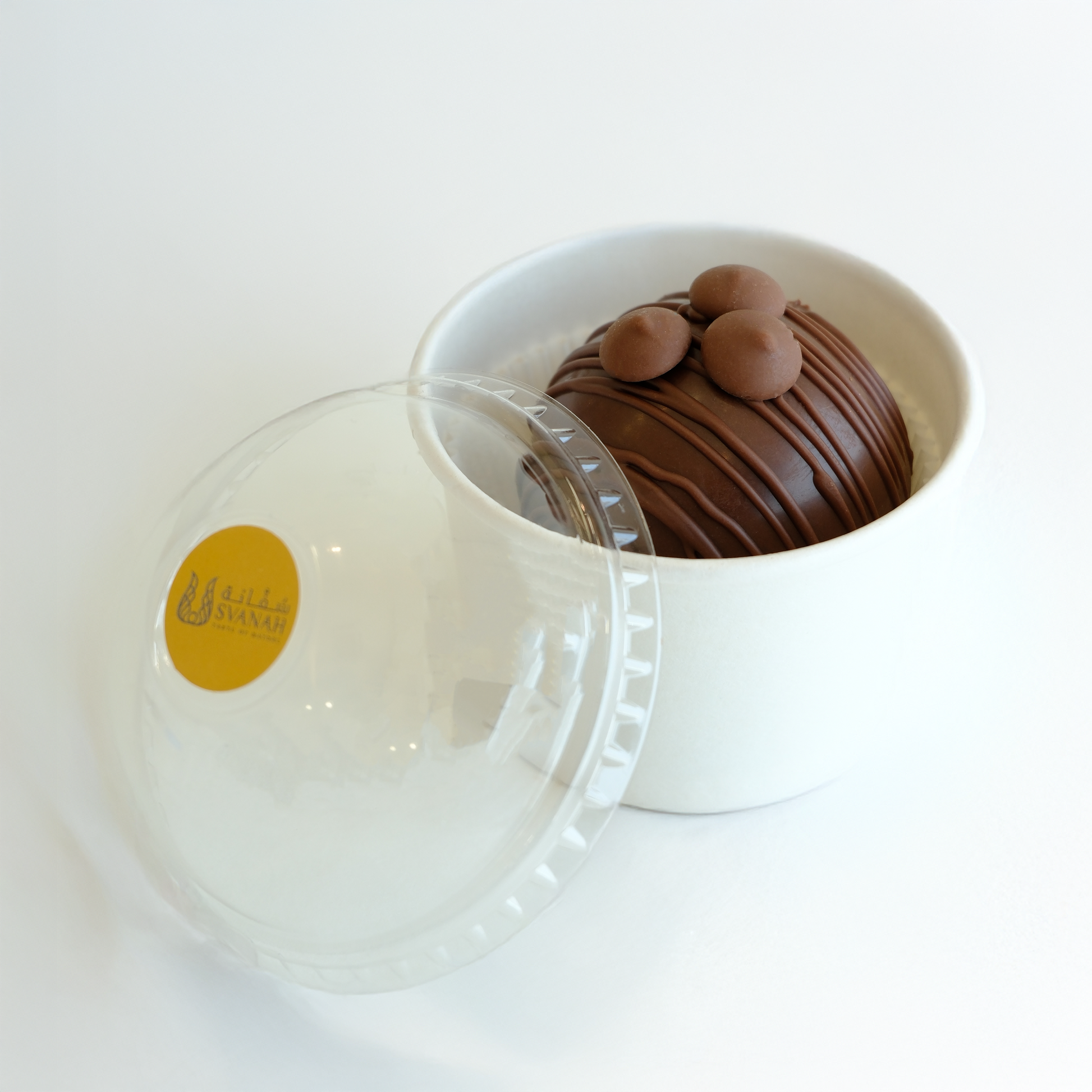 Chocolate dessert in a white container with a clear lid on a white background