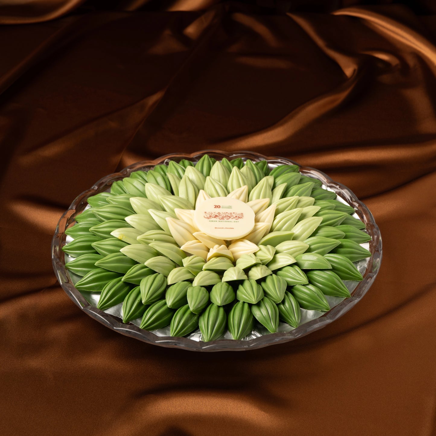 Omani National Day green chocolate tray arrangement shaped as a flower on a brown fabric background